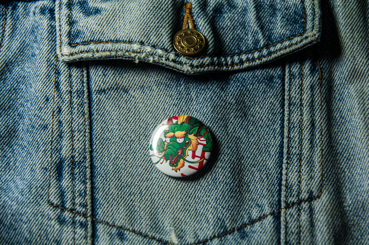Pin's de carpe Dragon sur une veste en jean. Fabrication artisanale.