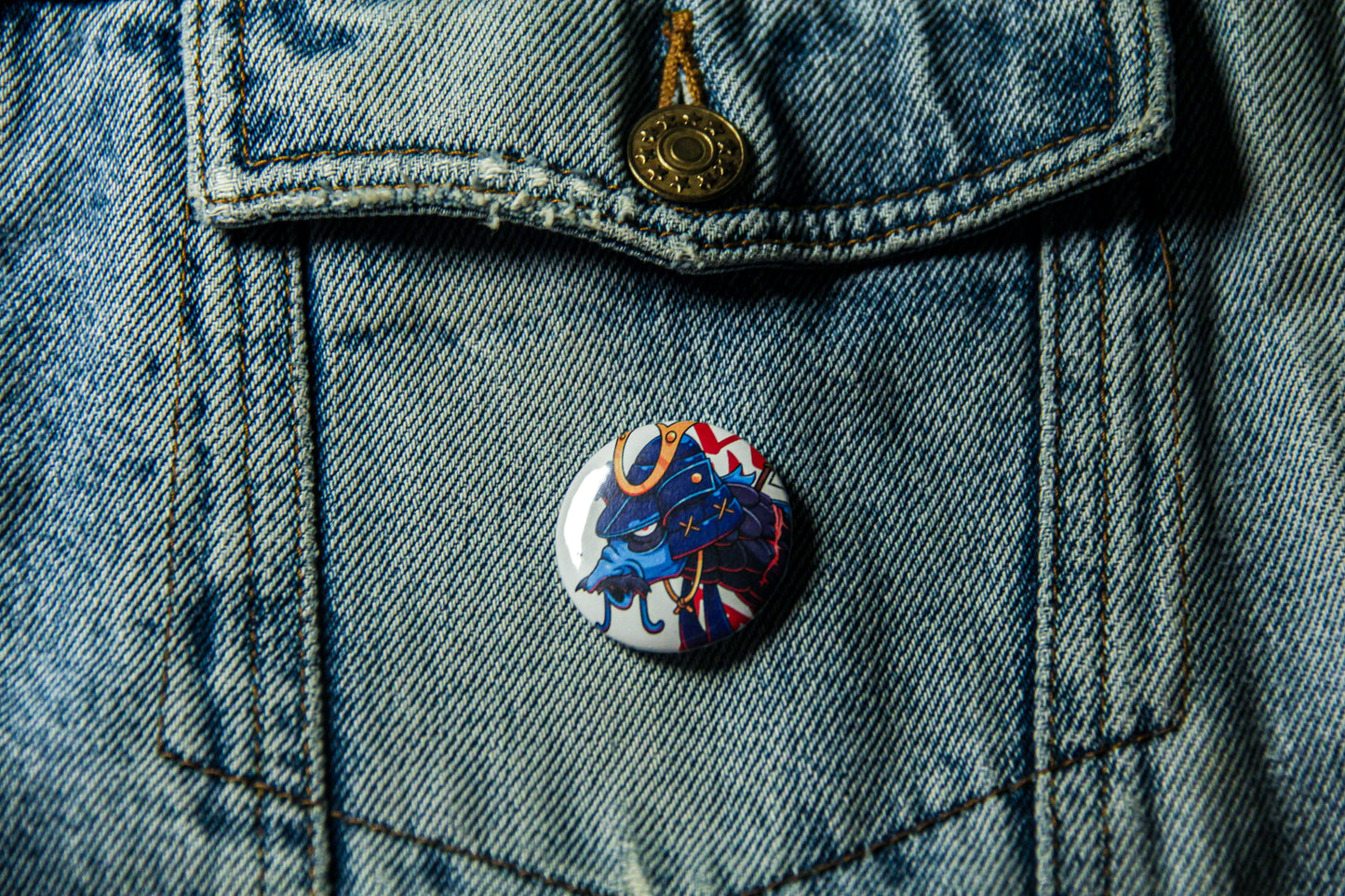 Pin's d'une carpe samourai bleue sur une veste en jean.