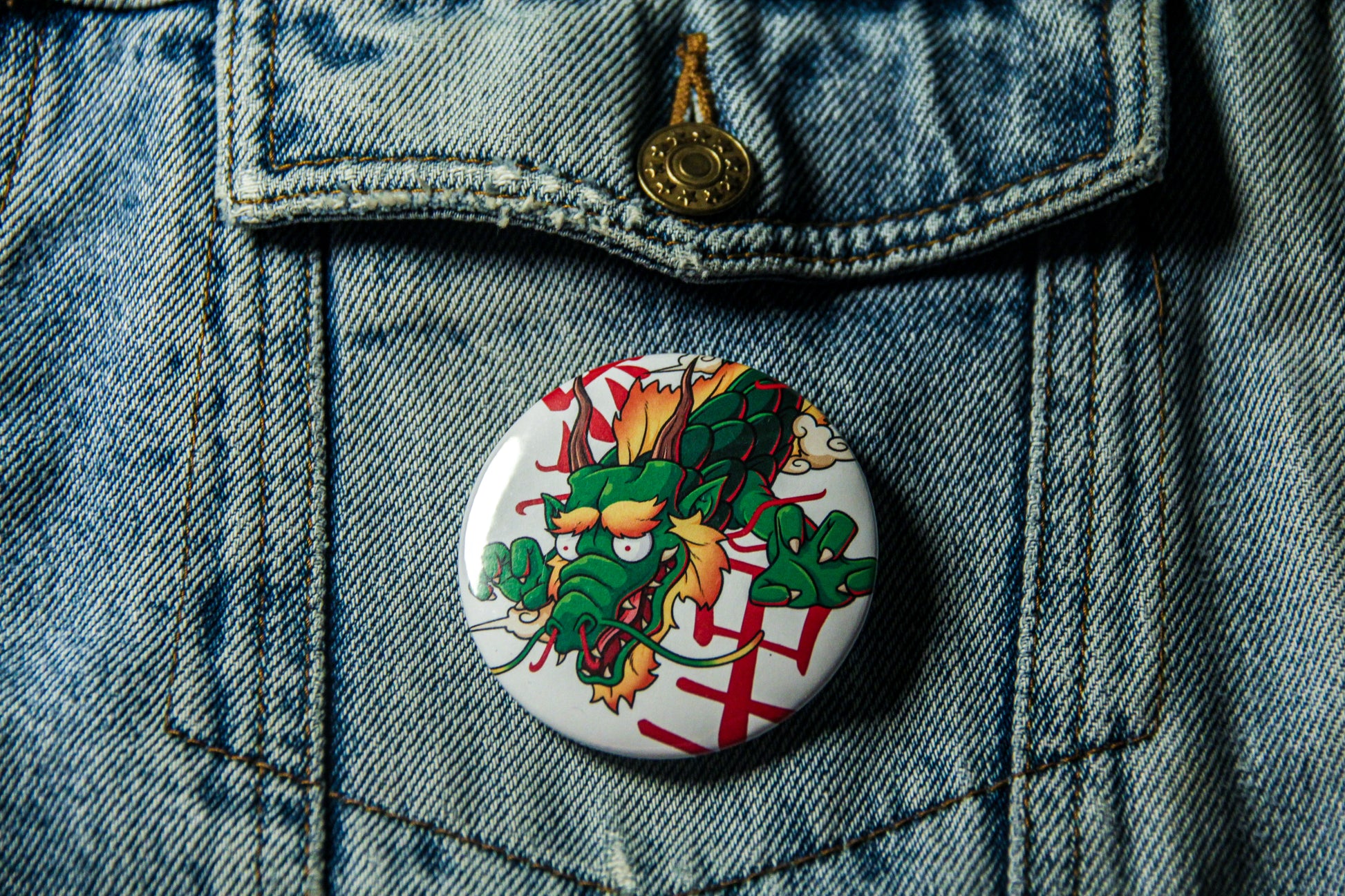 Pin's de carpe Dragon sur une veste en jean. Fabrication artisanale.