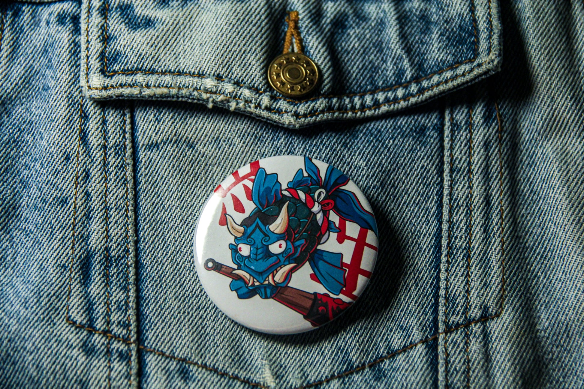 Pin's de carpe Oni sur une veste en jean. Fabrication artisanale.