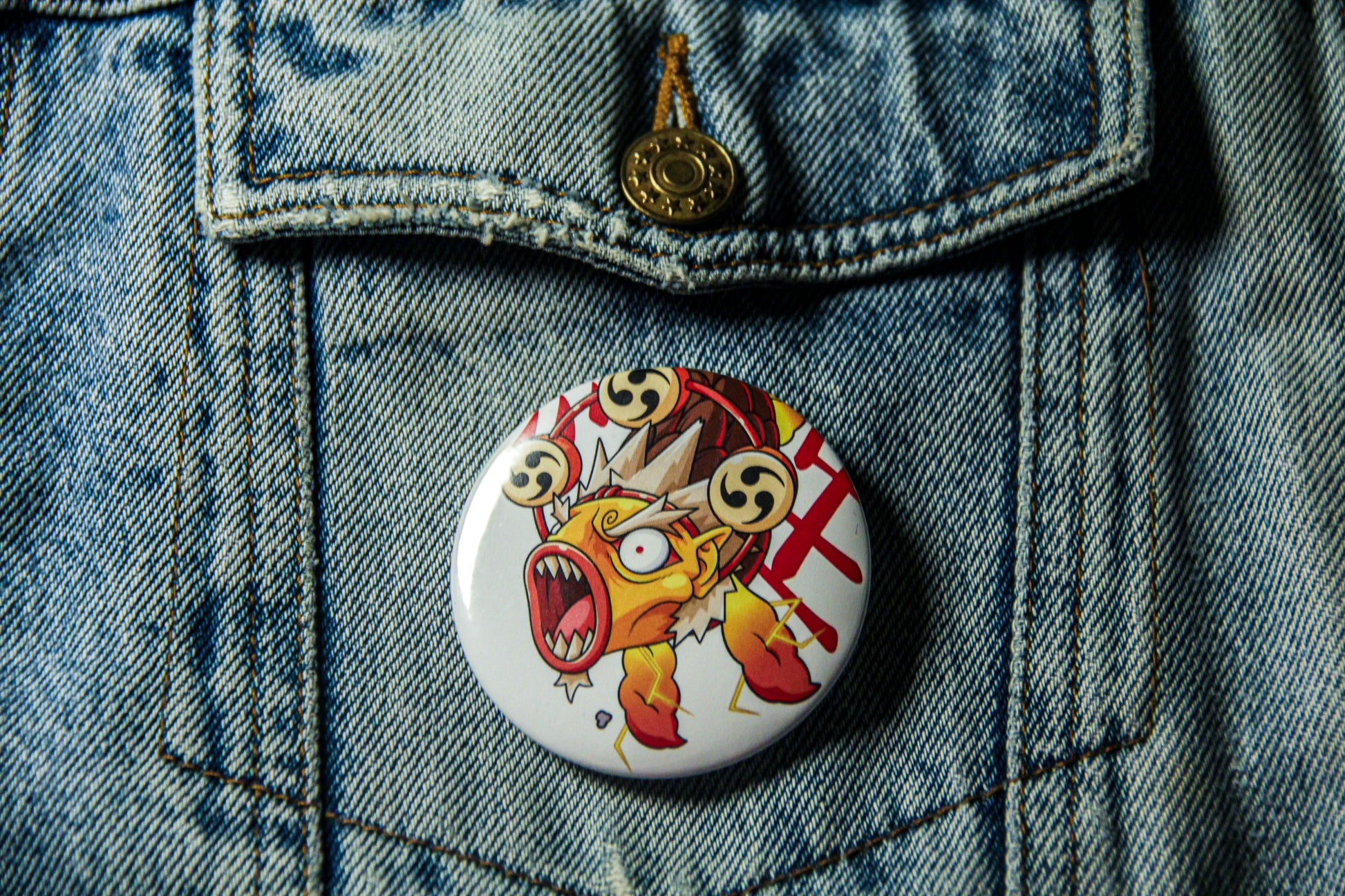 Pin's d'un carpe Raijin sur une veste en jean. Fabrication artisanale.