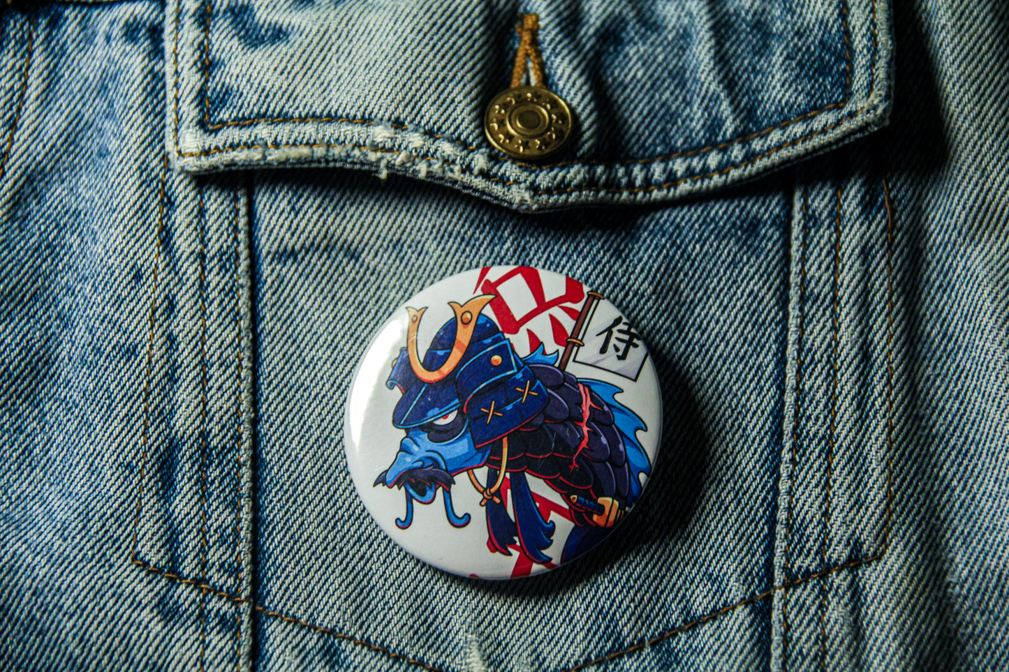 Pin's d'une carpe samourai bleue sur une veste en jean.