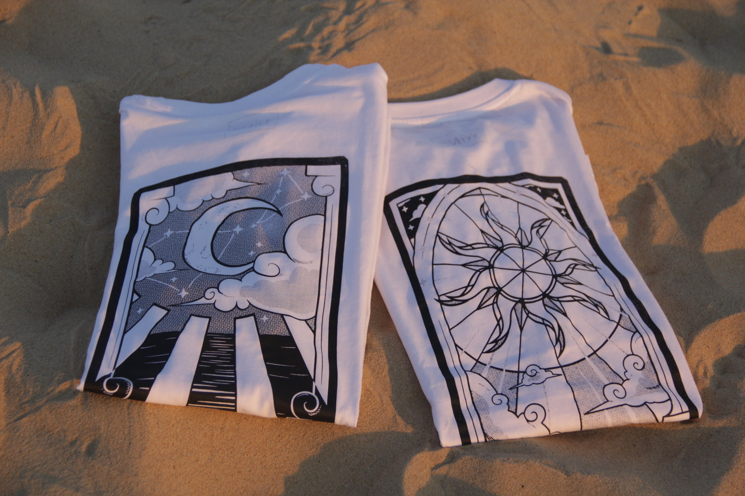 Deux T-Shirts assortis, pliés et posés sur le sable.