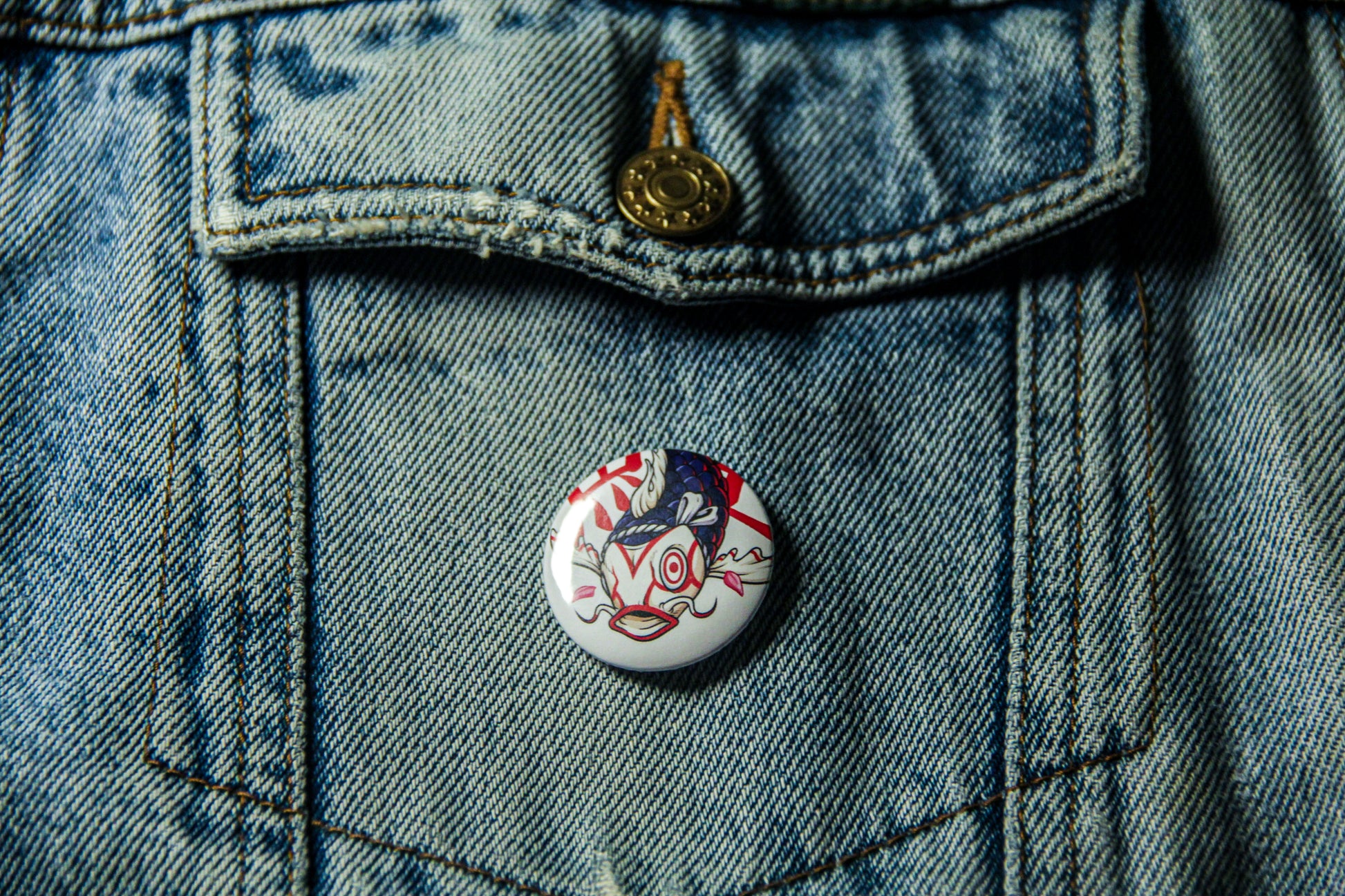 Pin's de carpe Kabuki sur une veste en jean. Fabrication artisanale. 